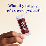 Hand holding a packet of Oom labs Oral Zen gag suppressant with text 'What if your gag reflex was optional?' on a beige background