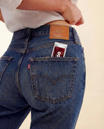 Woman wearing blue jeans with a Levi's logo, showing the back pocket which contains a packet of Oral Zen natural gag reflex control.